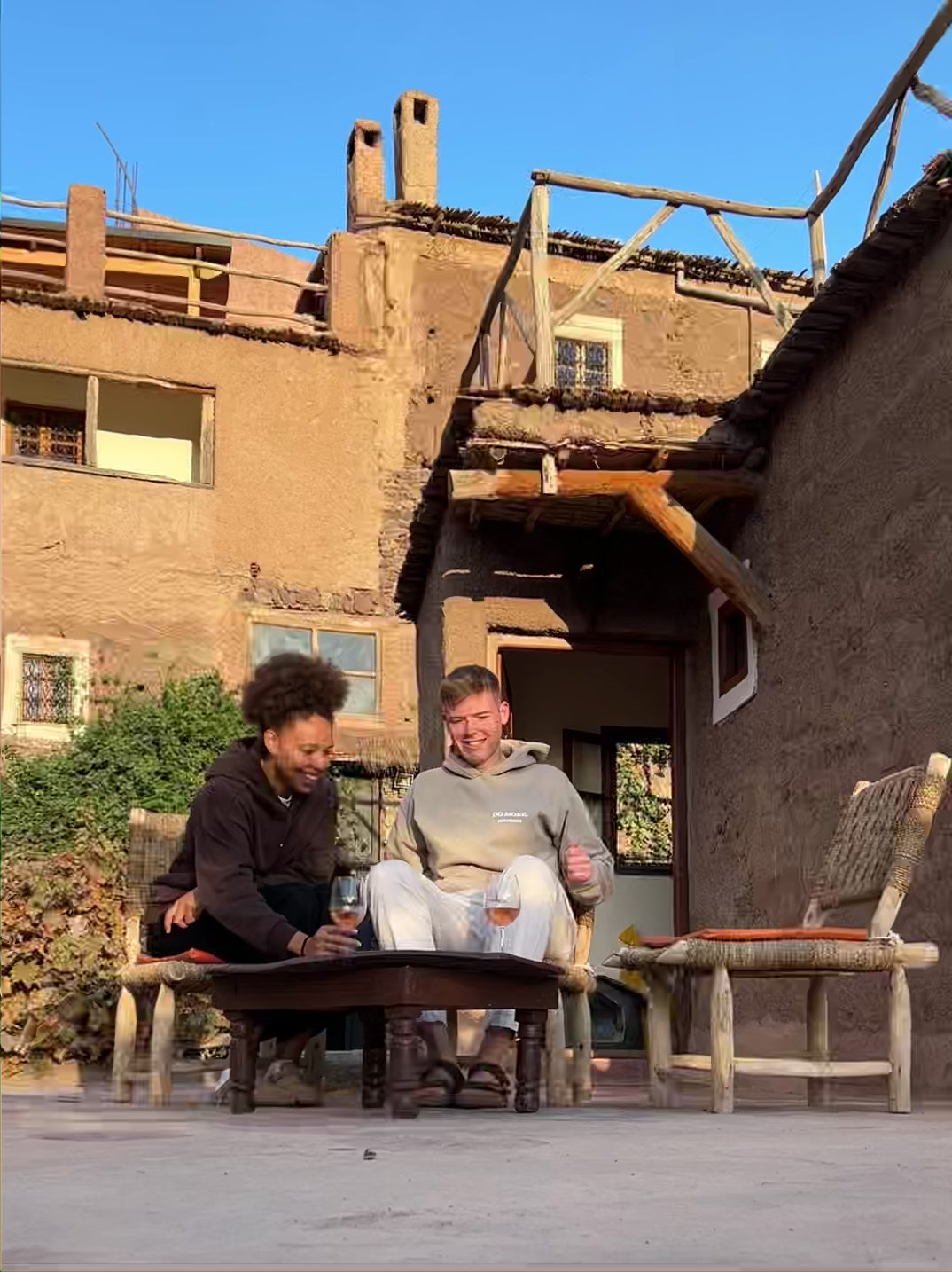 Video laden: Es ist ein Paar zu sehen, dass in einem entspannten Moment einen Wein vor einem Haus trinkt und sich küsst und lacht.